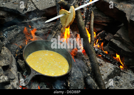 Les œufs sur le feu à iron pan frit avec du pain grillé sur une broche Banque D'Images