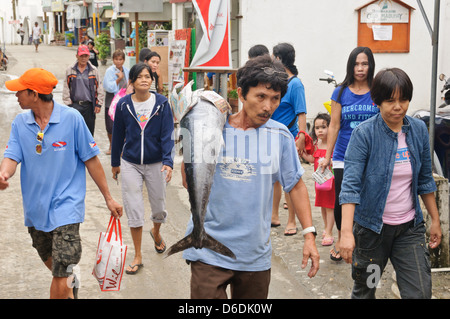 Pêcheur asiatique porte un gros poisson fraîchement pêché Wahoo Acanthocybium solandri dans la rue suivie par de nombreuses personnes, Sabang Asie Banque D'Images