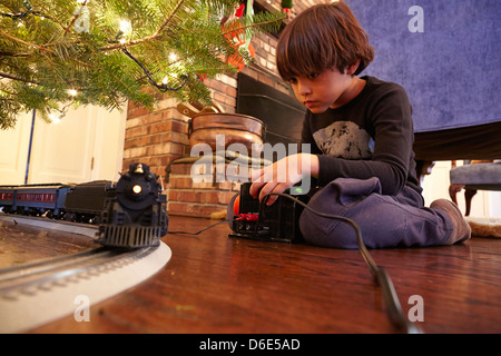 Mixed Race boy playing with christmas train Banque D'Images