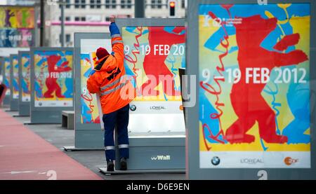 Un membre du personnel de la société de publicité de plein air Wall AG équipe les vitrines publicitaires avec Berlinale affiches lors de la Potsdamer Platz à Berlin, Allemagne, le 23 janvier 2012. À la 62e Berlinale allant du 09 au 19 février 2012 18 films seront en compétition pour l'Ours d'argent et d'or Prix du jury. Photo : Sebastian Kahnert Banque D'Images