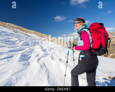 Une femme marche à travers l'affouillement sastrugi causés par le vent sur la neige au-dessus de Wrynose Pass, Lake District, UK. Banque D'Images