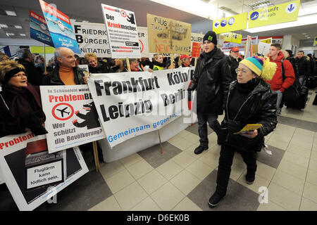 Les adversaires de la nouvelle Berlin Brandenburg Airport (BER) manifester contre le bruit des avions à côté des voyageurs à l'aéroport par un terminal zone d'arrivée à Berlin, Allemagne, 04 février 2012. La manifestation fait partie d'une campagne nationale de manifestation contre la piste nord-ouest de Francfort/Main et le bruit des avions. Photo : BERND SETTNIK Banque D'Images