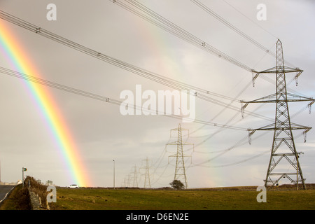 Un arc-en-ciel sur les pylônes électriques laissant nucléaire Wylfa sur l'Anglesey, au Pays de Galles, Royaume-Uni. Banque D'Images