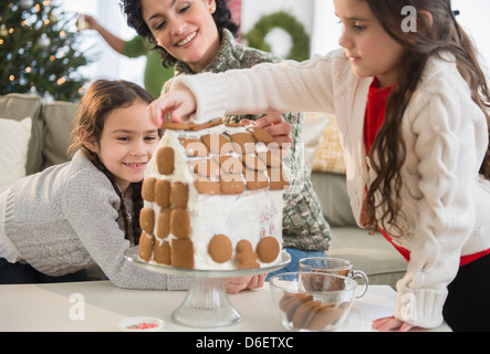 Mère et filles making gingerbread house Banque D'Images