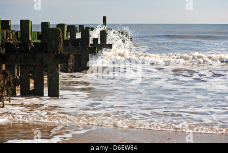 Vue d'un brise-lames en bois et l'action des vagues à Bacton-sur-Mer, Norfolk, Angleterre, Royaume-Uni. Banque D'Images