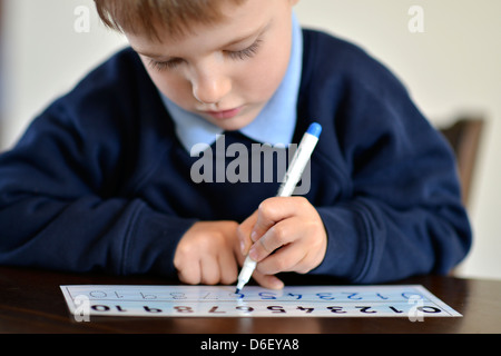 Un écolier de 5 ans apprendre à écrire les nombres. Banque D'Images