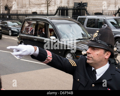 Policier pointant sur les manifestants à l'enterrement de Margaret Thatcher que le corbillard transportant le cercueil durs passé. Banque D'Images