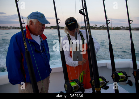 Crewman Jason Peer (R) examine les options de s'attaquer à la pêche Paul Rubin client à bord du navire affrété Lo Que Sea, Floride Banque D'Images