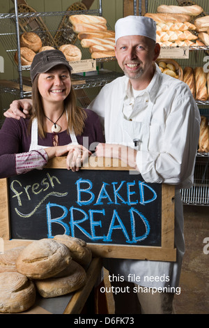 Portrait d'un mari et femme dans leur boulangerie commerciale, entouré par du pain frais Banque D'Images