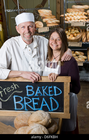 Portrait d'un mari et femme dans leur boulangerie commerciale, entouré par du pain frais Banque D'Images