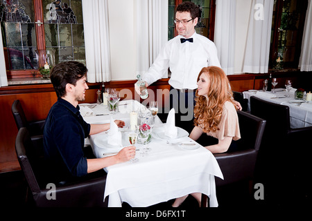 L'homme et la femme pour le dîner au restaurant waiter serving eau minérale Banque D'Images