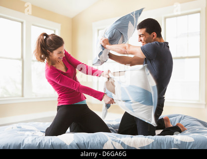 Couple having pillow fight on bed Banque D'Images