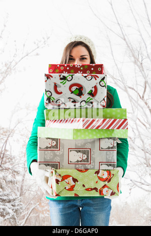 Caucasian woman holding Christmas gifts in snow Banque D'Images