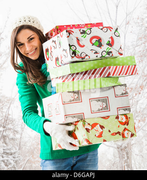 Caucasian woman holding Christmas gifts in snow Banque D'Images