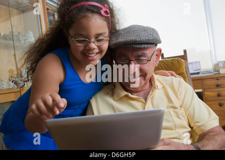 Older Hispanic man using digital tablet with granddaughter Banque D'Images