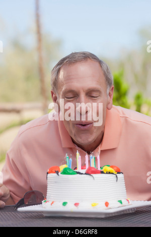 Plus man blowing birthday candles Banque D'Images