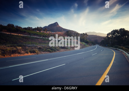 Road s'infiltre à travers vineyar au coucher du soleil à Stellenbosch. Une partie de la route des vins qui représente plus de 200 producteurs de raisin et de vin Banque D'Images