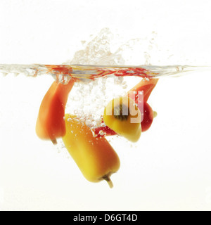 Piments multicolores aux éclaboussures dans l'eau Banque D'Images