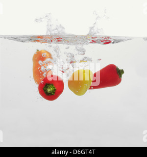 Piments multicolores aux éclaboussures dans l'eau Banque D'Images