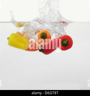 Piments multicolores aux éclaboussures dans l'eau Banque D'Images