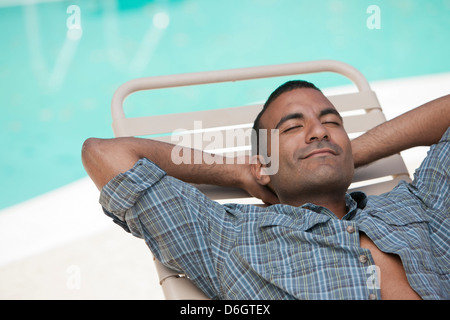 Man relaxing in pool par chaise de jardin Banque D'Images