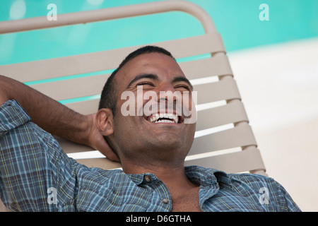 Man relaxing in pool par chaise de jardin Banque D'Images