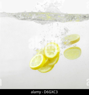 Les tranches de citron dans l'eau éclaboussant Banque D'Images