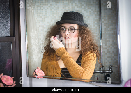 Woman applying makeup in mirror Banque D'Images