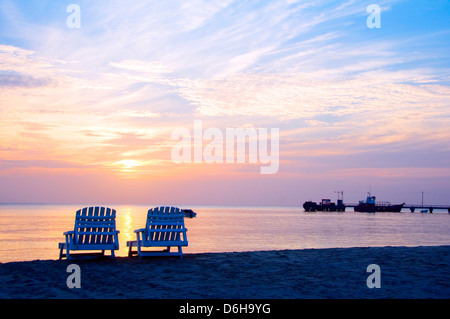 Coucher du soleil, le Centre de pique-nique plage avec chaises longues et des bateaux en mer des Caraïbes distance Big Corn Island Nicaragua Amérique Centrale Banque D'Images