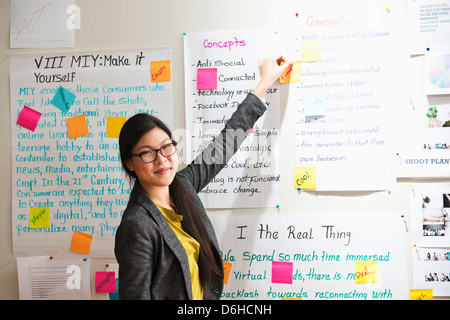 Femme avec des notes adhésives et des papiers sur le mur Banque D'Images