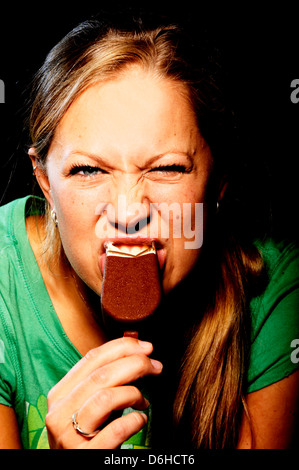 Une jeune femme mordre dans un magnum chocolat ice cream Banque D'Images