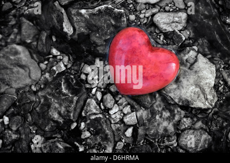 Coeur de pierre rouge au milieu de cailloux dans un ruisseau Banque D'Images
