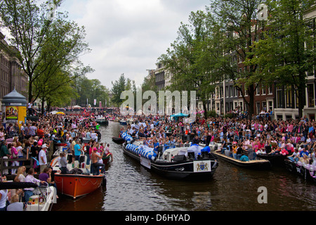 La parade de la Gay Pride dans un canal bordé de monde avec des personnes et des bateaux à Amsterdam, Hollande. Banque D'Images