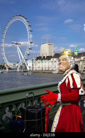 L'Angleterre, Londres. La reine Elizabeth imposteur souriant dans une robe rouge vif le long de la rivière Thames. Banque D'Images
