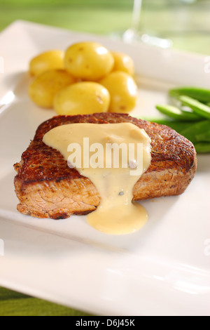 Médaillon de boeuf steak (filet mignon) avec sa sauce au poivre pommes beurrées et pois sugar snap sur une plaque carrée blanche Banque D'Images