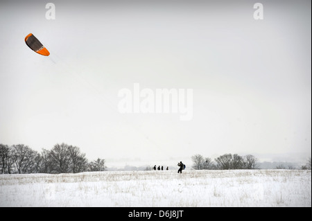 Un homme 'kitesurf' ou 'nowkiting' dans la neige sur Minchinhampton Common, Gloucestershire UK Banque D'Images