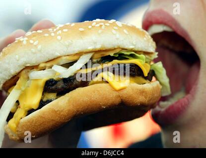 Fichier - une archive photo datée du 23 novembre 2003 montre une jeune femme mangeant un hamburger à Duesseldorf, Allemagne. Les experts de l'ONU sont d'avis que tous les aliments qui sont malsains dans de plus grandes quantités devraient devenir plus cher. Photo : Gero Breloer Banque D'Images