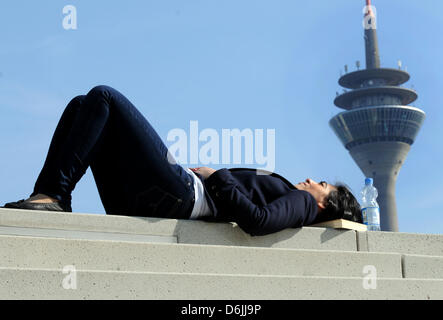 Frühlingsanfang : eine junge Frau liegt am Freitag (20.03.2012) à Düsseldorf im Medienhafen bei strahlendem Sonnenschein, blauem Himmel und Temperaturen um die13 Grad auf einer Steintreppe und sich sonnt.Im Hintergrund der Rheinturm. Auch in den nächsten Tagen bleibt uns das Wetter sonnige mit Temperaturen bis zu erhalten Grad18. Foto : Horst Ossinger dpa/lnw Banque D'Images