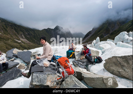 Les touristes de manger un déjeuner pique-nique sur le Fox Glacier. L'île du Sud, Nouvelle-Zélande Banque D'Images