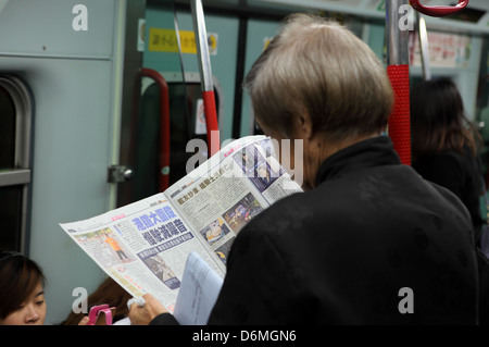 Lire Hong Kong, Chine, dans un métro passager au journal Banque D'Images
