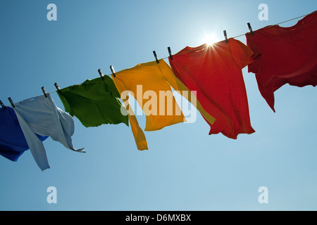 Soleil qui brille sur un fil à linge avec des vêtements sur un jour de vent. Banque D'Images
