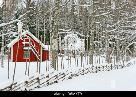 Petite maison peinte en rouge traditionnelle suédoise et marron, recouvert de neige. Banque D'Images