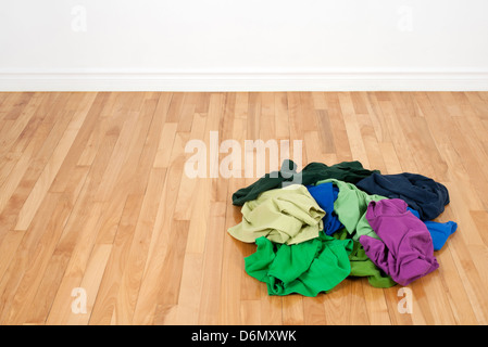 Pile de vêtements très colorés sur le parquet dans la chambre vide. Banque D'Images