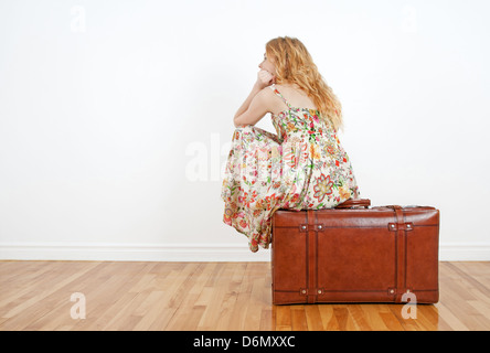 Girl wearing robe d'été est assis sur une valise vintage, d'anticiper et de voyage en attente. Banque D'Images