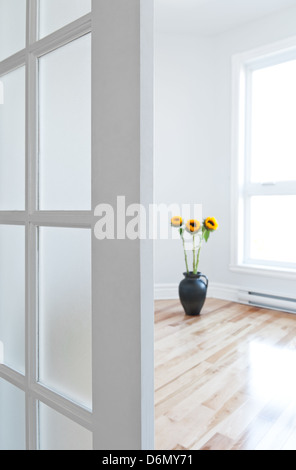 Ouvert porte donnant dans une chambre contemporaine pleine de lumière, ornées de fleurs. Banque D'Images