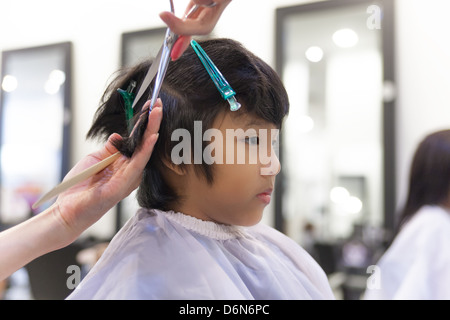 Un jeune garçon se coupe au salon de coiffure Banque D'Images