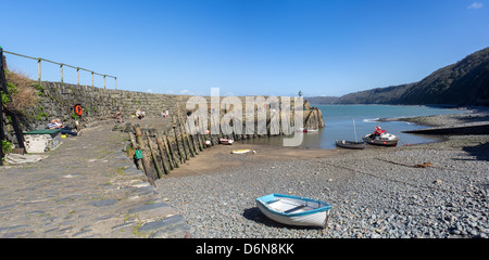 Clovelly, Devon, Angleterre. Le 19 avril 2013. Port de Clovelly avec ciel bleu et plage de galets avec des gens assis sur le quai Banque D'Images