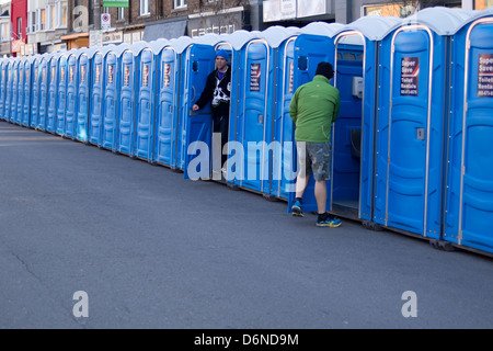 Une personne entre dans un portable alors qu'un autre sort d'une toilette portative de l'avant du 2013, rue Yonge Toronto 10K Banque D'Images