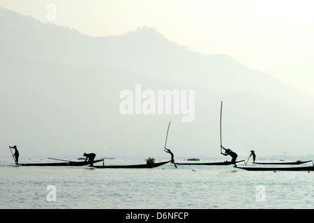 Les pêcheurs sur le lac Inle en battant l'eau avec des perches en bambou pour obtenir le poisson dans leurs filets Banque D'Images