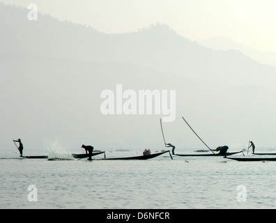 Les pêcheurs sur le lac Inle en battant l'eau avec des perches en bambou pour obtenir le poisson dans leurs filets Banque D'Images